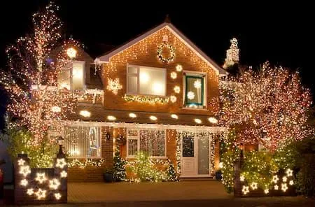 Home and trees covered in multicolor lights with lit stars
